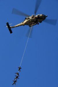 US Navy 061205-N-8158F-253 Sailors assigned to Explosive Ordnance Disposal Mobile Unit One One (EODMU-11), Detachment Three, soar high in the sky attached to an SH-60 Seahawk photo