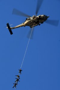 US Navy 061205-N-8158F-253 Sailors assigned to Explosive Ordnance Disposal Mobile Unit One One (EODMU-11), Detachment Three, soar high in the sky attached to an SH-60 Seahawk