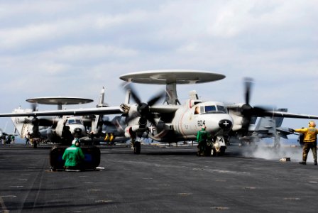 US Navy 061207-N-6106R-004 An aircraft director signals the pilots of an E-2C Hawkeye, from Carrier Airborne Early Warning Squadron One One Five (VAW-115) the Liberty Bells, onto the waist catapult prior to starting flight ope