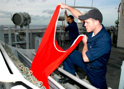 US Navy 061210-N-8547M-006 Quartermaster Seaman Jeff Schulze removes the bravo flag to raise aboard amphibious assault ship USS Saipan (LHA 2) while Quartermaster 3rd Class Wilfred Gonzalez holds the rope in place