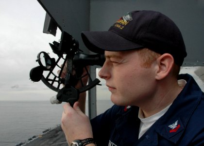 US Navy 061210-N-8547M-005 Quartermaster Jason A. Lentz uses a sextant to take a sun shot from the bridge wing of the pilothouse of amphibious assault ship USS Saipan (LHA 2)
