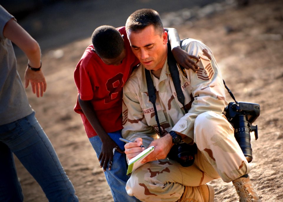 US Navy 061212-N-1328C-150 U.S. Air Force Master Sgt. Scott Wagers, from Atlanta, Ga., writes down the name of an orphan at a boy's orphanage while photographing service members from Camp Lemonier and Combined Joint Task Force
