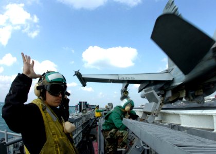 US Navy 061219-N-8907D-002 A Sailor with V-2 Division waist safety gives the all clear to launch an F-A-18C Hornet
