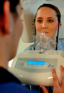 US Navy 061216-N-5345W-005 Hospitalman Kori Prough sits in the crosshairs while receiving training from Hospital Corpsman 3rd Class Sarah Bullard on how to properly align patients while operating the dental department's new dig