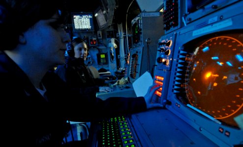 US Navy 061216-N-5345W-038 Operations Specialist 2nd Class Carly King watches as Operations Specialist 3rd Class Ashley Tarsio works at her Advanced Combat Direction System (ACDS) console in the Combat Direction Center (CDC)