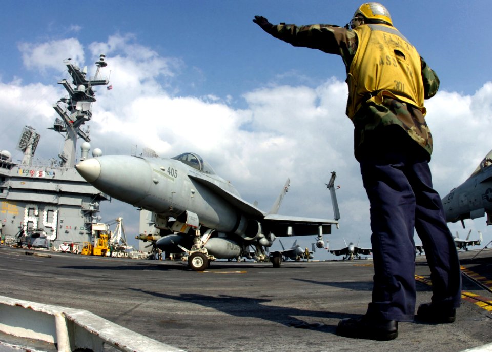 US Navy 061219-N-8907D-001 An aircraft director signals to a F-A-18C Hornet from the Wildcats of Strike Fighter Squadron One Three One (VFA-131) prior to launch aboard the Nimitz-class aircraft carrier USS Dwight D. Eisenhower