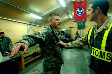 US Navy 061212-N-8148A-129 A Navy customs border clearance agent inspects a soldier assigned to the Army's 82nd Airborne Division for any possible unauthorized objects that could be concealed in his uniform