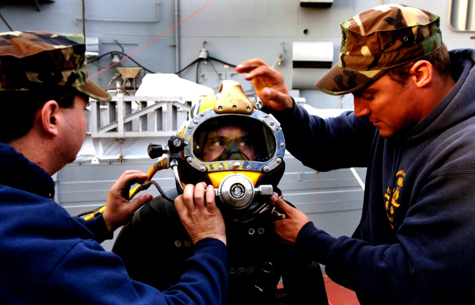 US Navy 070104-N-9769P-024 Working directly with Southwest Regional Maintenance Center (SWRMC) divers, Senior Chief Mass Communication Specialist (diver) Andrew McKaskle is fitted with the MK-21 diving helmet before documenting