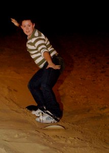 US Navy 061222-N-5330L-364 Electrician's Mate 2nd Class Sabrina Hornberger, assigned to the Nimitz-class aircraft carrier USS Dwight D. Eisenhower (CVN 69) slides down a sand dune on a snowboard during a Morale Welfare and Recr
