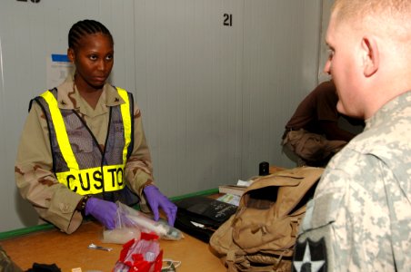 US Navy 061223-N-5758H-113 Storekeeper 3rd Class Natasha Ogarro, assigned to Navy Customs Battalion Romeo, inspects and searches the belongings of a soldier to ensure his luggage is contraband free at an air base in Southwest A