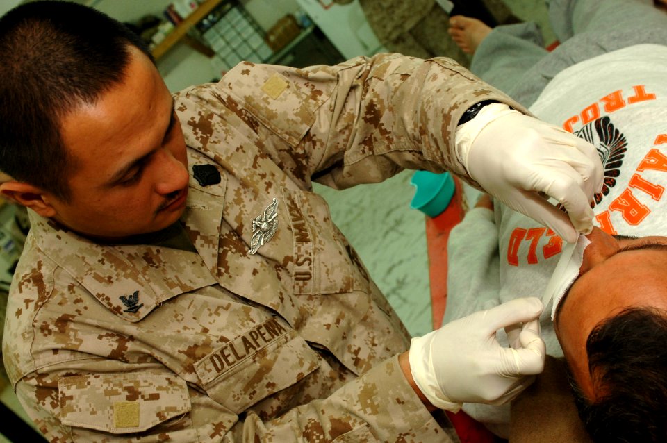 US Navy 061220-N-5758H-086 Hospital Corpsman 3rd Class Aloen Delapena, assigned to the 1st Medical Battalion, Camp Pendleton, applies clean bandages to a wound on the face of an Iraqi citizen