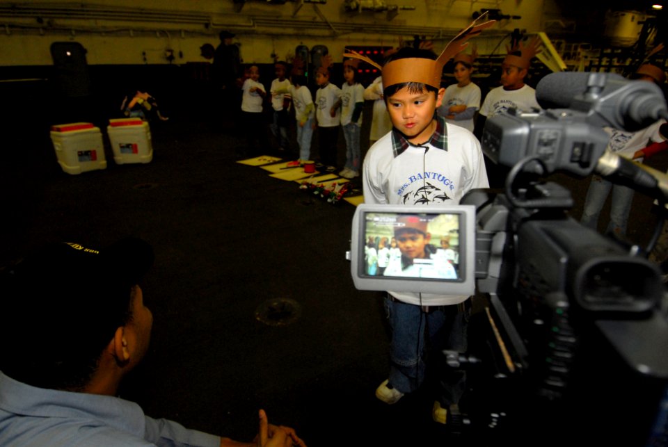 US Navy 061219-N-6106R-101 Mass Communication Specialist Seaman Benjamin Dennis, from Queens, N.Y., interviews kid from The Sullivans Elementary School, aboard USS Kitty Hawk (CV 63)