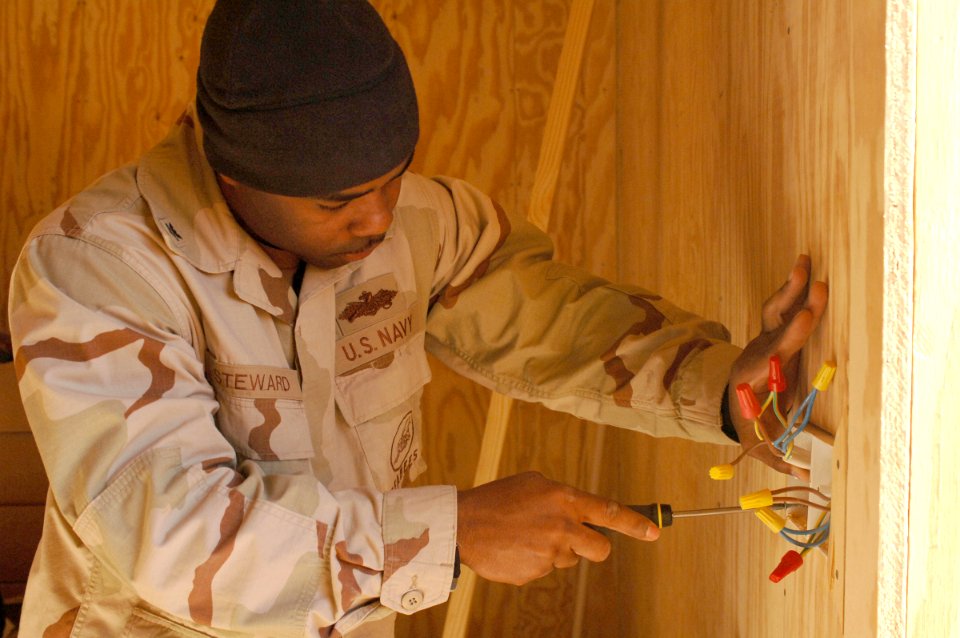 US Navy 061220-N-0193M-036 Construction Electrician 2nd Class Nathaniel Steward inserts a plastic casing around wires that will eventually become a light switch