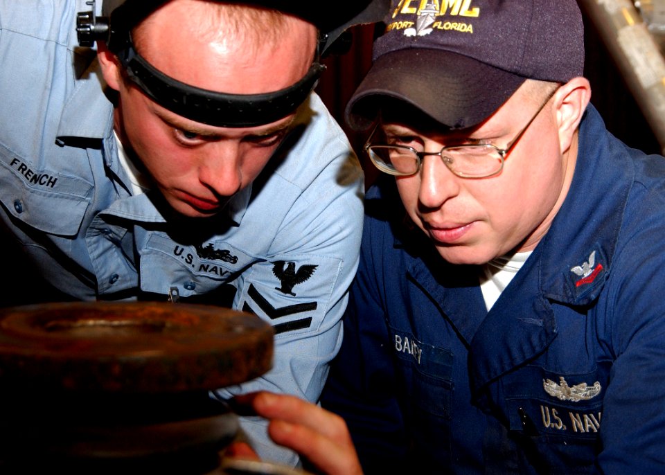 US Navy 070103-N-3285B-051 Hull Technician 2nd Class Christopher French and Mervin Bailey inspect welds on an expansion bellows that they are repairing for the guided-missile cruiser USS Hue City (CG 66)