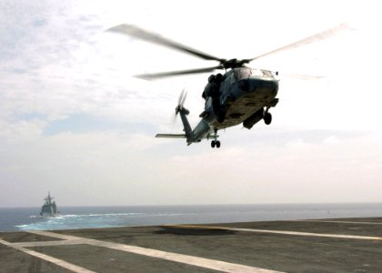 US Navy 070108-N-0490C-001 The Ticonderoga-class guided-missile cruiser USS Anzio (CG 68) steams behind the Nimitz-class aircraft carrier USS Dwight D. Eisenhower (CVN 69) as an SH-60F Seahawk prepares to land on Eisenhower's f