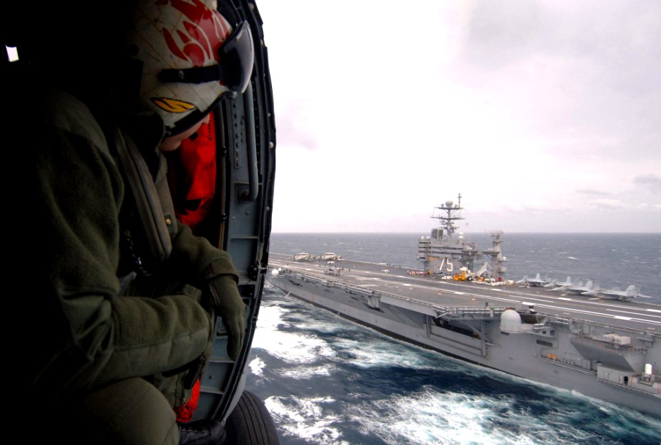 US Navy 070116-N-0535P-030 Aviation Warfare Systems Operator 2nd Class David Musser, attached to the Red Lions of Helicopter Anti-Submarine Squadron One Five (HS-15), looks out the door of an SH-60 Seahawk while a