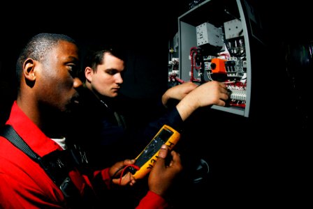 US Navy 070122-N-3729H-039 Electrician's Mate Fireman Cecil Harper, left, and Electrician's Mate Fireman James Werderman, check circuit connections on a cardboard disposal system aboard the Nimitz-class aircraft carrier USS Joh
