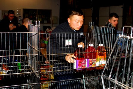 US Navy 070117-N-1831S-025 Storekeeper 3rd Class Young Kim, assigned aboard the amphibious transport dock USS Nashville (LPD 13), stocks a cart with food items at the South Eastern Hampton Roads Food Bank