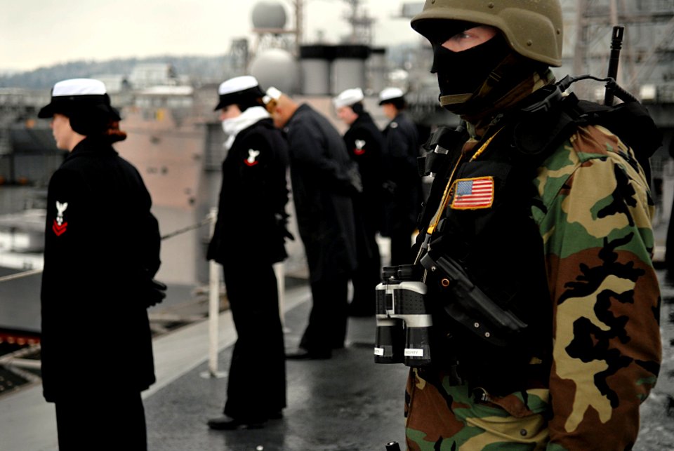 US Navy 070116-N-0684R-072 A security guard stands watch while Sailors man the rails as the USS John C. Stennis (CVN 74) departs Naval Base Kitsap Bremerton for a scheduled deployment