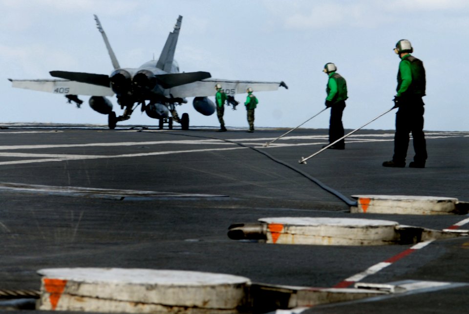 US Navy 070121-N-0684R-115 Flight deck personnel from air department prepare to guide an arresting gear cable back to its housing after an F-A-18C Hornet attached to the Argonauts of Fighter Squadron One Four Seven (VFA-147) s