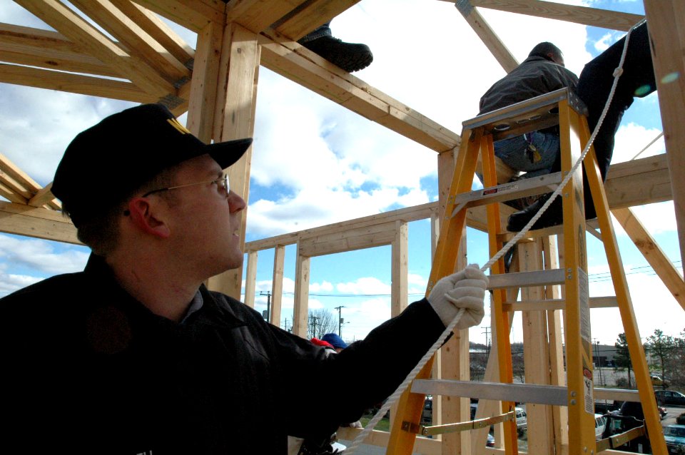 US Navy 070117-N-2456S-107 Seaman Robert Purcell, a Sailor stationed aboard amphibious transport dock USS Nashville (LPD 13), holds a safety line to help move a roof truss to the top of a house being built for Habitat for Human