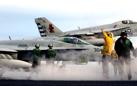 US Navy 070128-N-7130B-087 Sailors aboard USS Ronald Reagan (CVN 76) prepare an F-A-18C Hornet assigned to Strike Fighter Squadron One One Three (VFA-113) for launch as an F-A-18E Super Hornet performs a touch and go