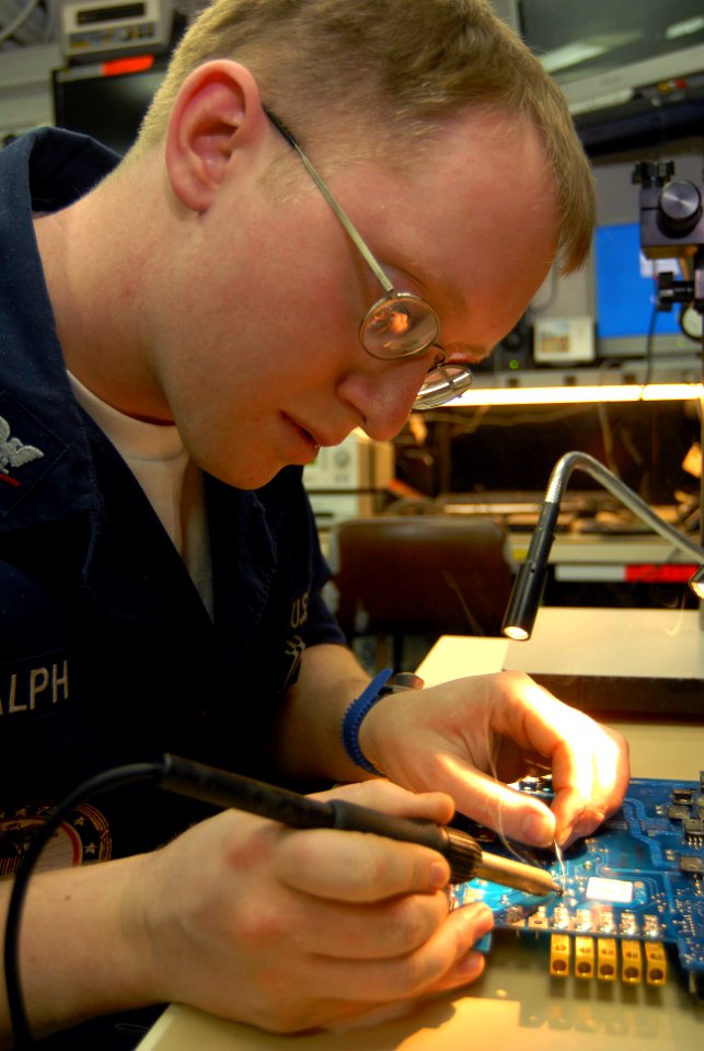 US Navy 070129-N-3038W-073 Electronics Technician 3rd Class Christopher Ralph makes repairs with a soldering iron on a circuit board in the micro-miniature electronics repair shop
