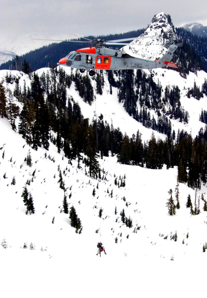 US Navy 070125-N-9150R-143 Helicopter in-flight rescue crewmen hang from an MH-60S Seahawk search and rescue (SAR) helicopter during a training mission in the North Cascade Mountains