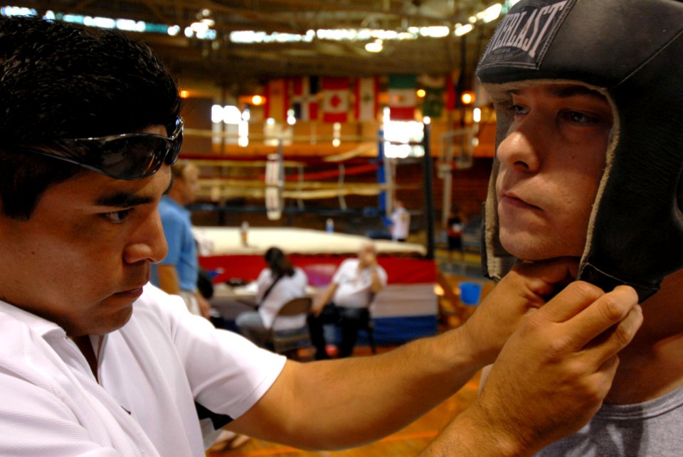 US Navy 070119-N-4965F-007 A boxing trainer from USA Boxing Hawaii Association, Inc., adjust the headgear of Electronics Technician 3rd Class Anthony Skillman