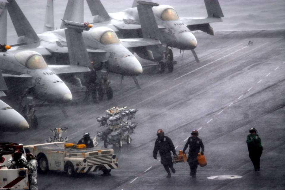 US Navy 070130-N-2959L-071 Personnel working on the flight deck of USS Ronald Reagan (CVN 76) grab their equipment and rush for shelter from an ongoing rain shower