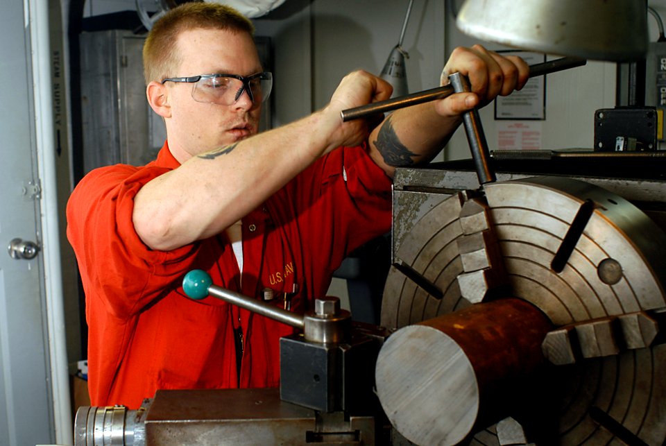 US Navy 070126-N-3038W-016 Machinery Repairman 2nd Class Jeremy Cambron prepares the lathe for making a tool to clean threads inside deck sockets in the machining shop aboard the Nimitz-class aircraft carrier USS John C. Stenni