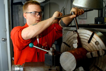 US Navy 070126-N-3038W-016 Machinery Repairman 2nd Class Jeremy Cambron prepares the lathe for making a tool to clean threads inside deck sockets in the machining shop aboard the Nimitz-class aircraft carrier USS John C. Stenni