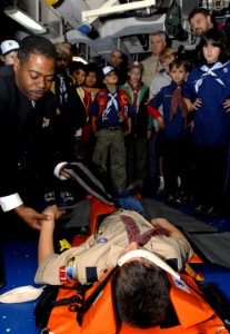 US Navy 070127-N-4954I-020 With the assistance of a webelos scout from Cub Scout Pack 774, Chief Mass Communication Specialist Anthony Briggs demonstrates the correct use of a backboard stretcher aboard USS Peleliu (LHA 5)