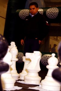 US Navy 070124-N-3038W-088 Electrician's Mate 2nd Class Robert Ramirez ponders his next move on the giant chess board during the Morale Welfare and Recreation events held in the hangar bay of the Nimitz-class aircraft car