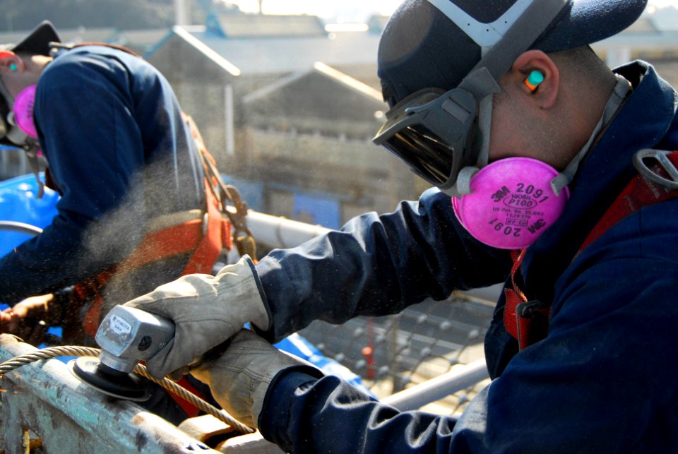 US Navy 070126-N-6106R-031 Aviation Boatswain's Mate (Handling) Airman Brandon Cruz from Bronx, N.Y., sands part of USS Kitty Hawk's (CV 63) flight deck to prepare the surface for painting