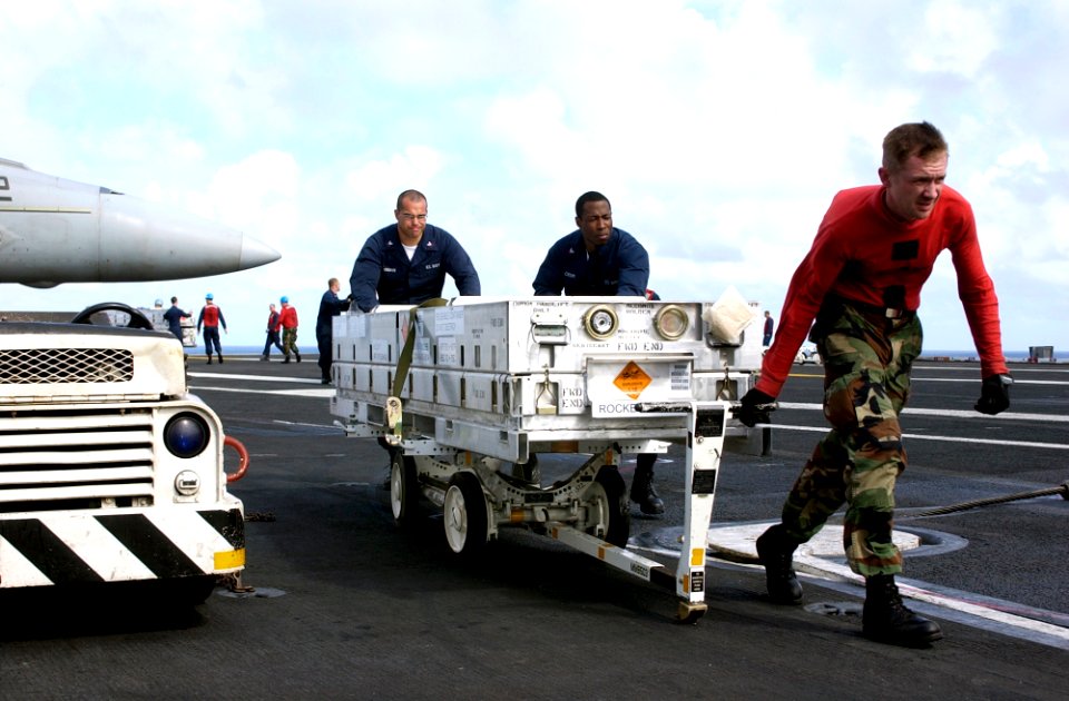 US Navy 070201-N-7130B-023 Combat systems department members assigned to USS Ronald Reagan (CVN 76) wheel empty ordnance boxes across the flight deck following an ordnance handling evolution