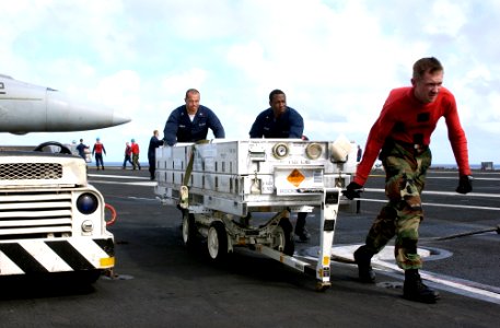 US Navy 070201-N-7130B-023 Combat systems department members assigned to USS Ronald Reagan (CVN 76) wheel empty ordnance boxes across the flight deck following an ordnance handling evolution