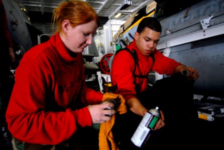 US Navy 070128-N-2659P-121 Aviation Ordnanceman Airman Juan Ovales hands tools to Aviation Ordnanceman 3rd Class Katherine Gutherie as they perform maintenance on a bomb rack injection foot