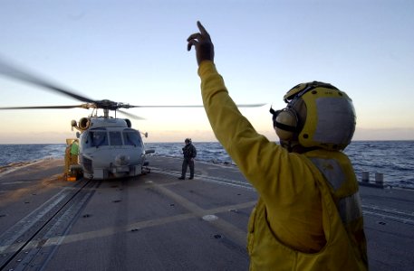 US Navy 070125-N-8534H-002 Boatswain's Mate 3rd Class Willie Ellerbe signals to the pilot of the SH-60B Seahawk that personnel are on the deck and in the danger zone aboard the guided missile frigate USS Gary (FFG 51)
