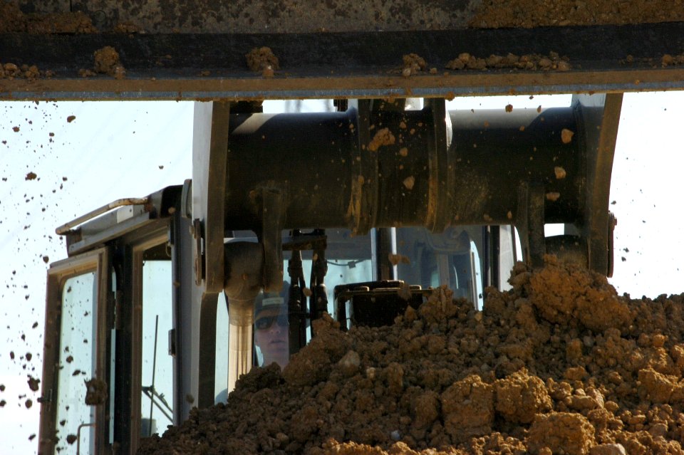 US Navy 070125-N-0775Y-044 Construction Electrician 2nd Class T.J. Crawford, a Seabee assigned to Naval Mobile Construction Battalion Three (NMCB-3), empties a load of dirt into a dump truck during a runway repair exercise at K