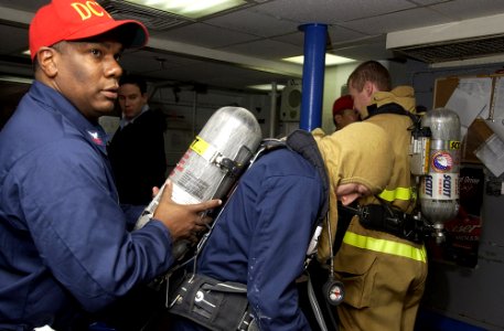 US Navy 070126-N-8534H-006 Damage control training team member Master-at-Arms 1st Class Devon Wilson assist a shipmate during dress out for a general quarters drill aboard the guided missile frigate USS Gary (FFG 51)