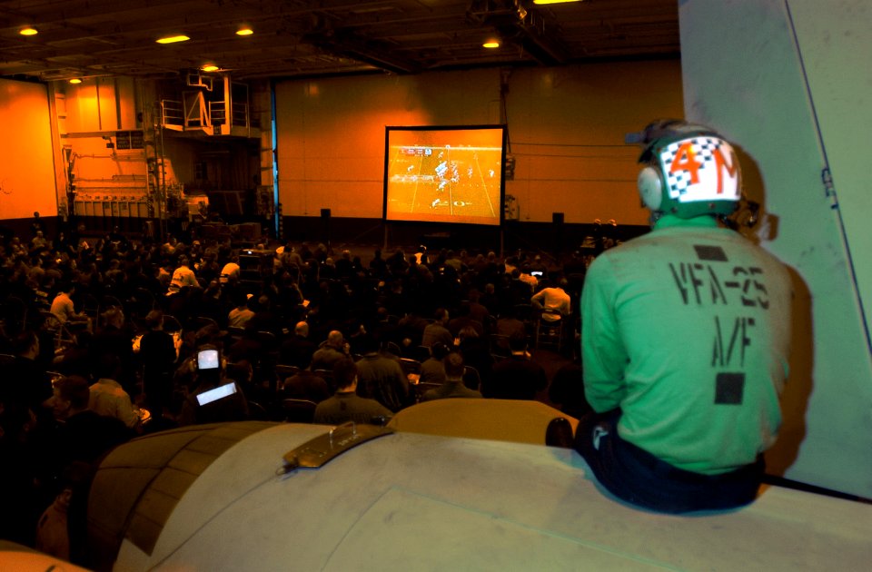 US Navy 070204-N-4009P-053 Aviation Structural Mechanic Airman Daniel Dingman from Pflugerville, Texas, watches Super Bowl XLI from the tail end of an F-A-18C Hornet in hangar bay two aboard Nimitz-Class aircraft carrier USS Ro