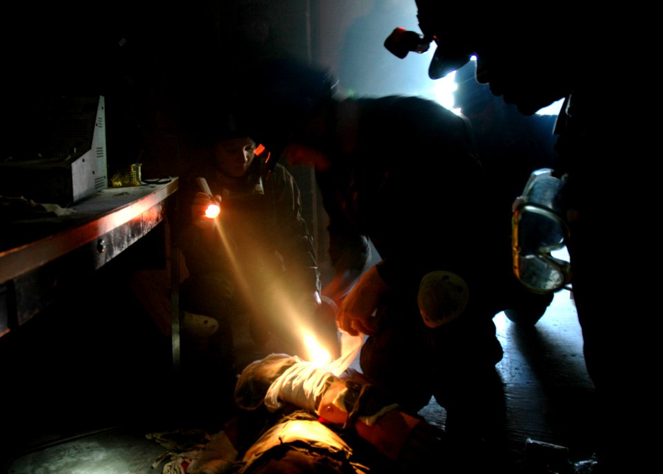 US Navy 070126-N-3857R-007 Equipment Operator Constructionman Caroline Yarmala, assigned to Naval Mobile Construction Battalion One (NMCB-1), helps assess the condition of a survivor during a mass casualty drill