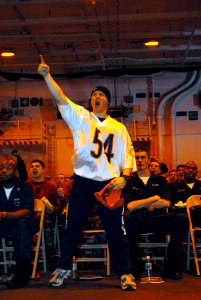 US Navy 070204-N-2959L-084 Wearing his Chicago Bears football attire, Storekeeper 3rd Class Derek Kimes from Freeport, Ill., jumps into the air in celebration of a touchdown while he watches Super Bowl XLI