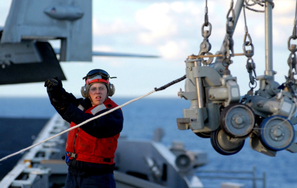 US Navy 070131-N-2959L-020 Fire Controlman 2nd Class Kenneth Breeden, from Corpus Christi, Texas, signals to the crane operator while sending two hand trucks to the NATO Sea Sparrow Missile platform