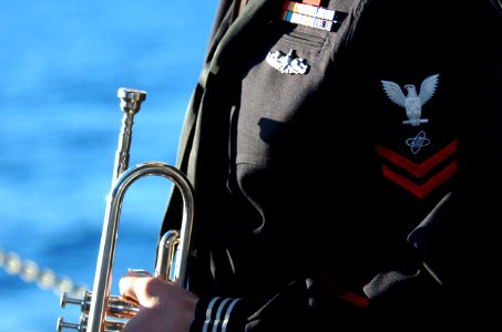 US Navy 070130-N-0555B-018 His trumpet polished to a brilliant shine, Electronics Technician 2nd Class Matthew Rohloff, from Monroe, Wis., plays the role of bugler during a burial at sea held aboard USS Ronald Reagan (CVN 76)