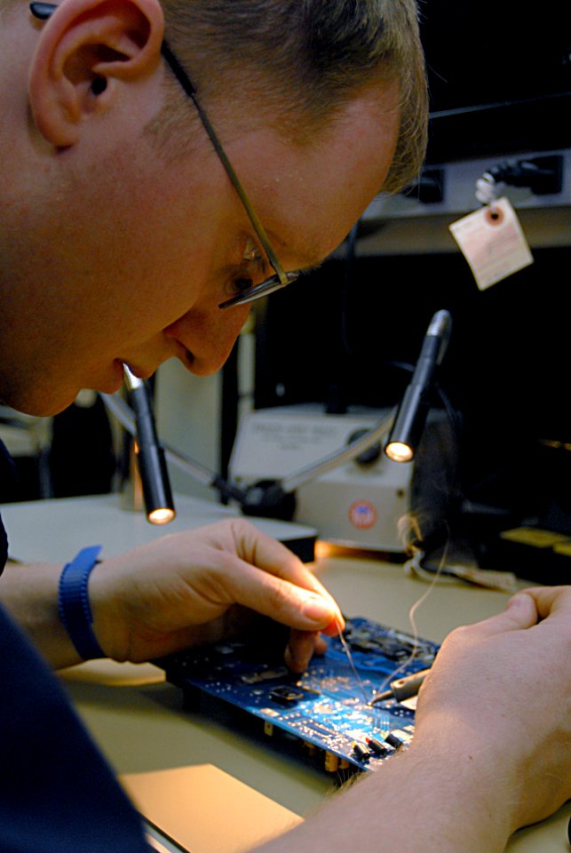 US Navy 070129-N-3038W-059 Electronics Technician 3rd Class Christopher Ralph uses a soldering iron to make repairs on a circuit board in the micro-miniature electronics repair shop aboard the Nimitz-class aircraft carrier USS