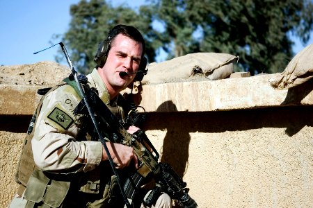 US Navy 070201-N-0000X-003 Lt. Brandon Scott, an instructor pilot with Strike Fighter Squadron (VFA) 122, crouches beside a wall