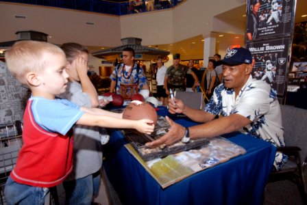 US Navy 070208-N-4965F-001 A young patron hands a football to Willie Brown, Hall of Fame cornerback for the Oakland Raiders, during an autograph signing session at the Pearl Harbor Navy Exchange photo