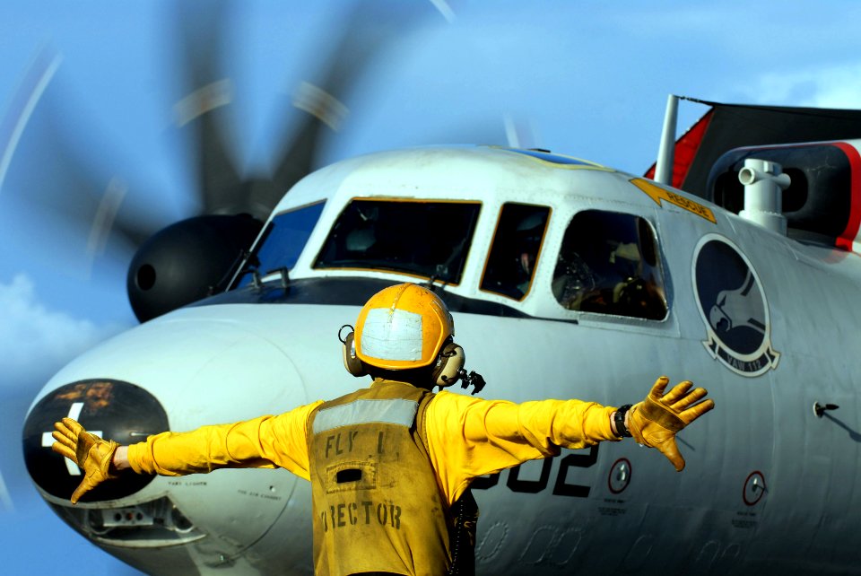 US Navy 070204-N-0684R-046 A flight deck director signals the pilot of an E-2C Hawkeye assigned to the Golden Hawks of Carrier Airborne Early Warning Squadron One One Two (VAW-112) to spread his wings